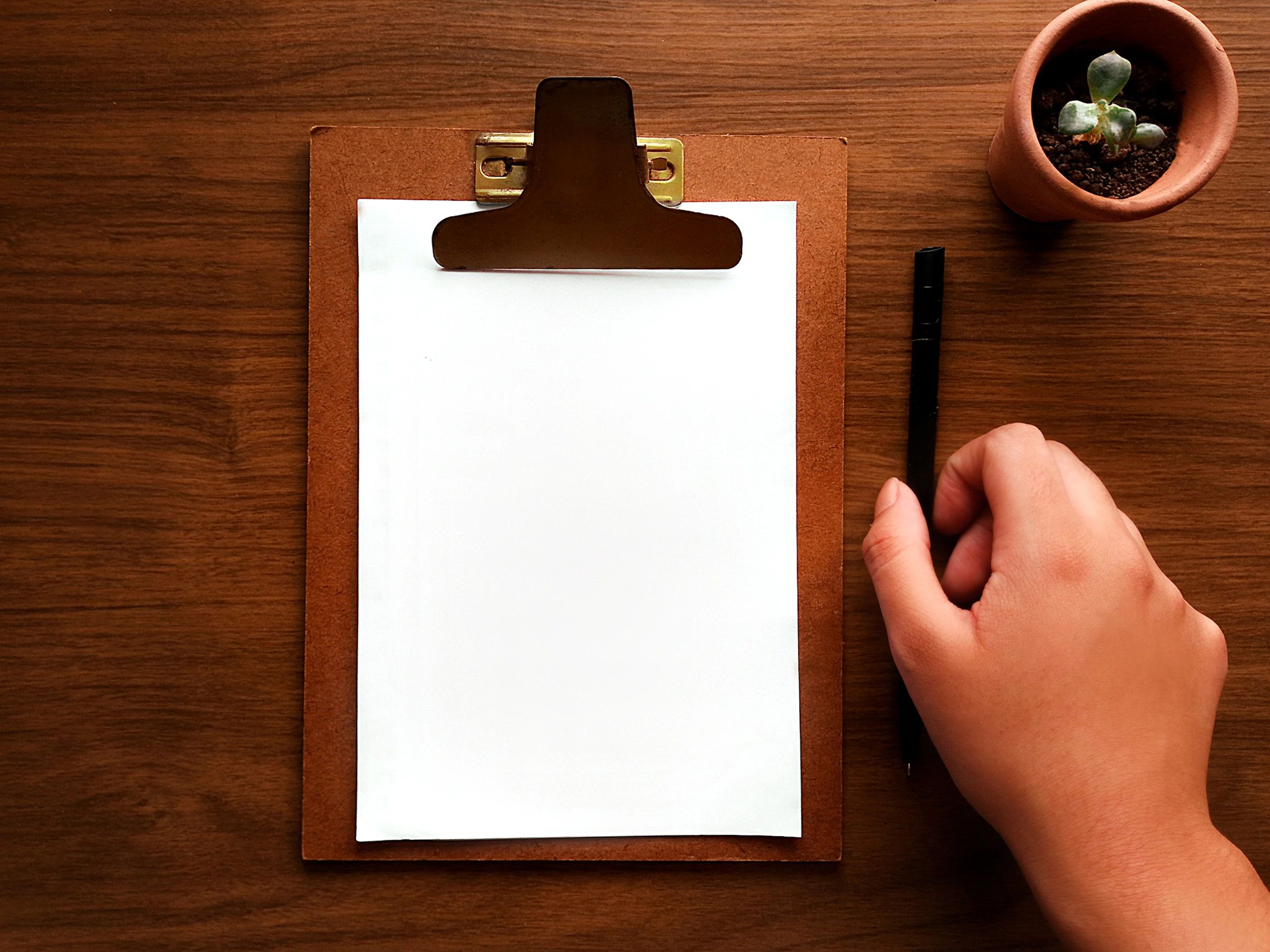 Writing desk with clipboard and pen on a wooden surface
