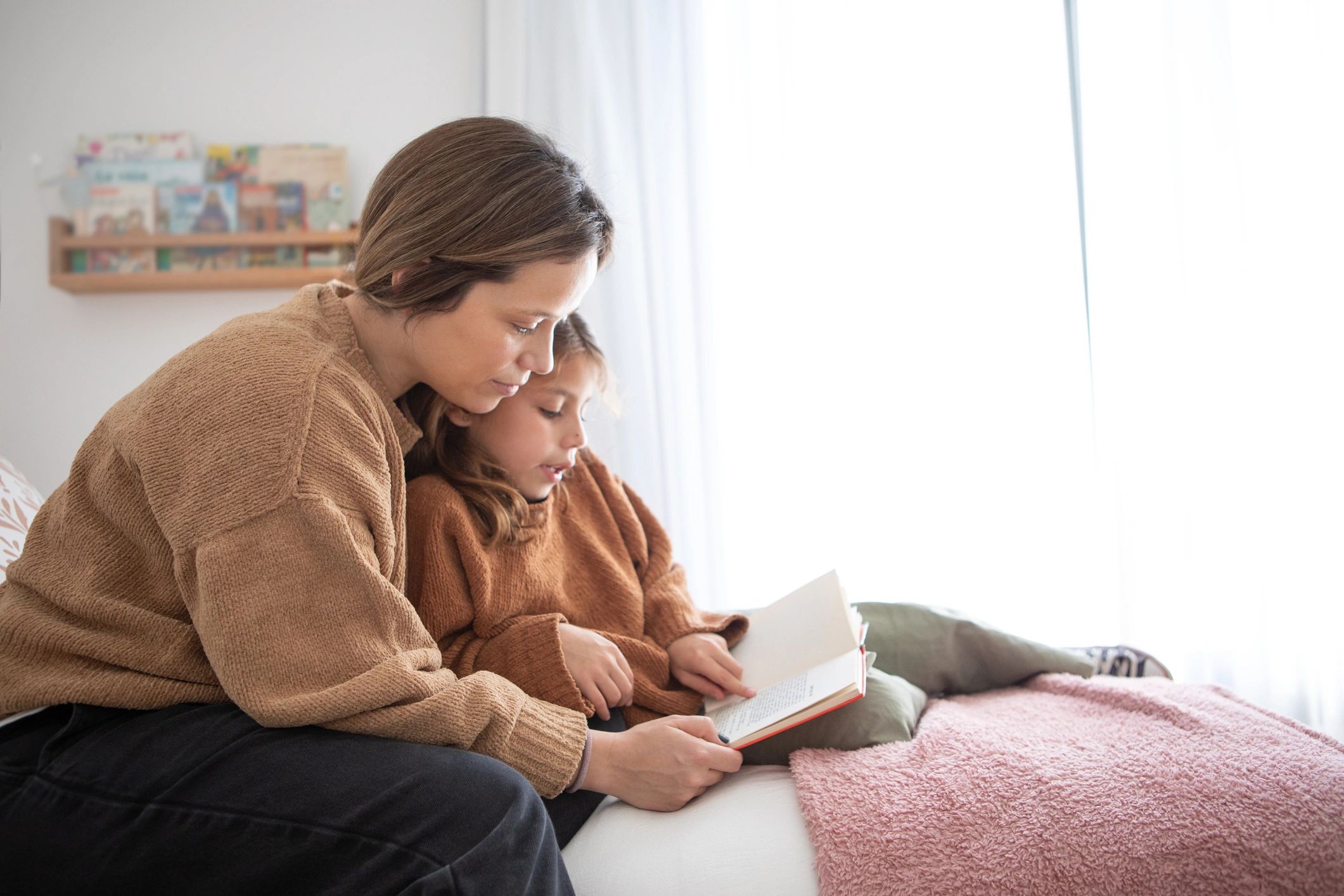 Mother and daughter reading a children's story in the bedroom