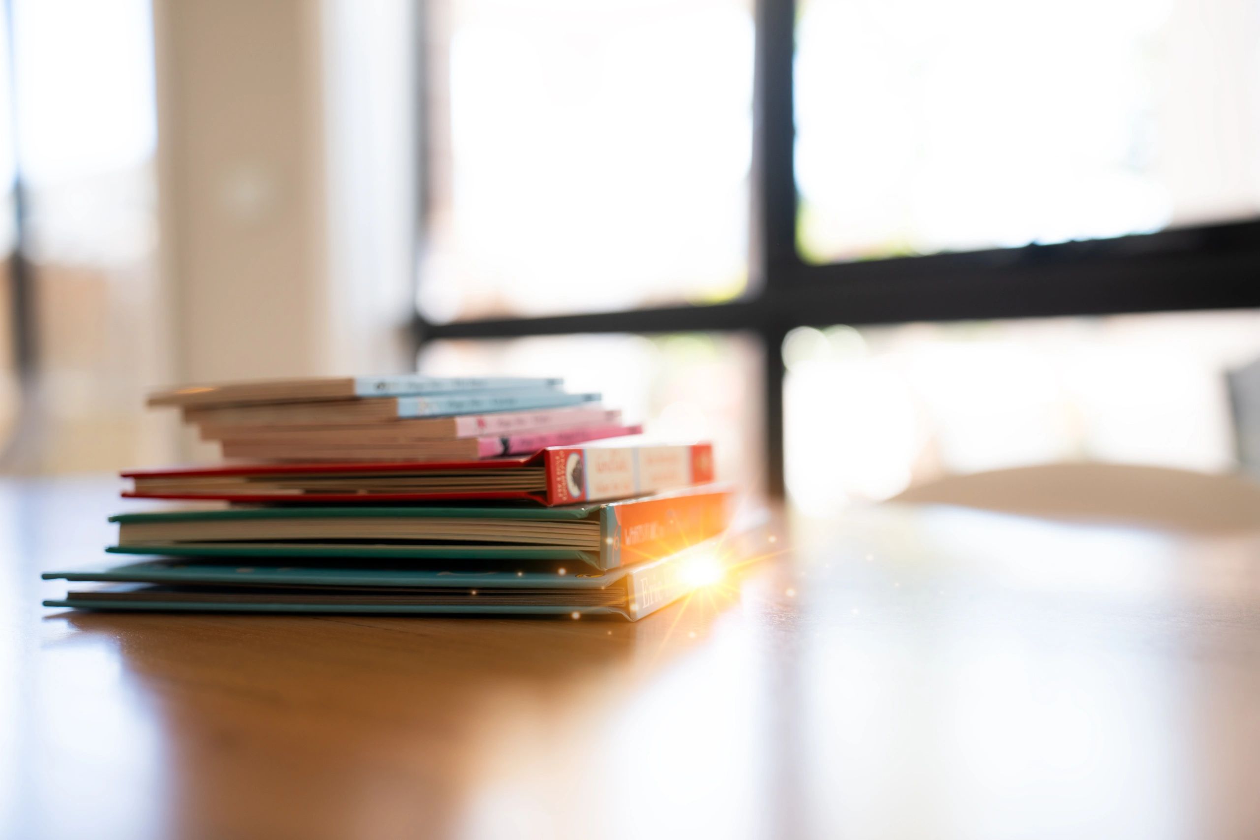 Stack of books on a wooden table in soft natural light